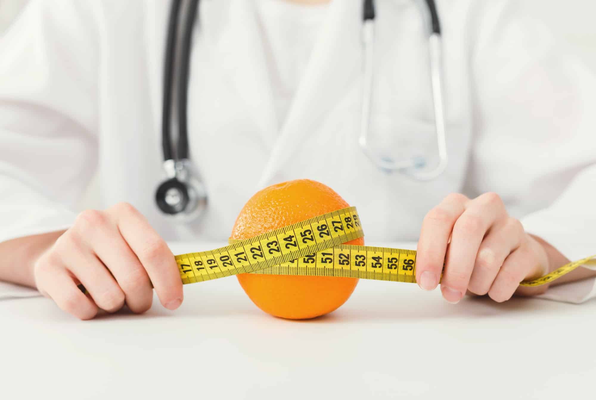Nutritionist doctor with fruit and measuring tape